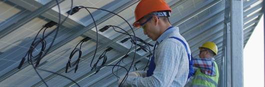 Workers connecting wires of solar panels